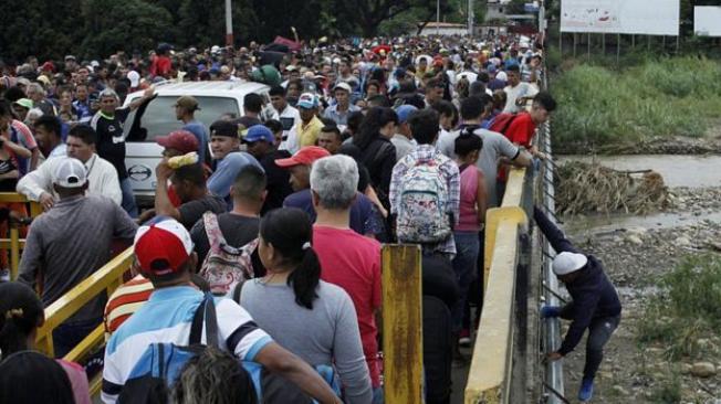 Cientos de personas forman fila para cruzar la frontera que los separa de Colombia en su intento por emigrar a otros países.