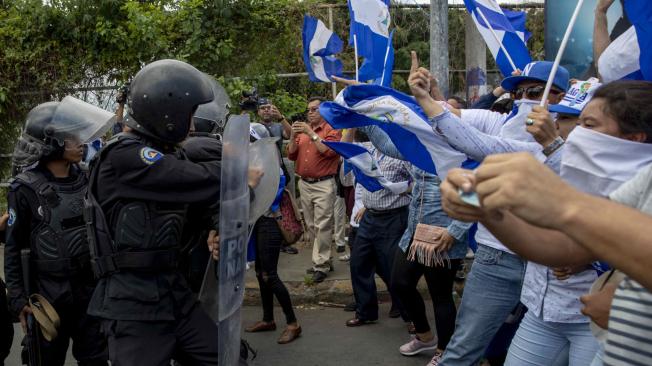 Manifestantes gritan consignas frente a un policía durante la marcha llamada " La Marcha de las Banderas" en contra el gobierno del presidente Daniel Ortega el domingo 2 de septiembre de 2018, en Managua (Nicaragua).