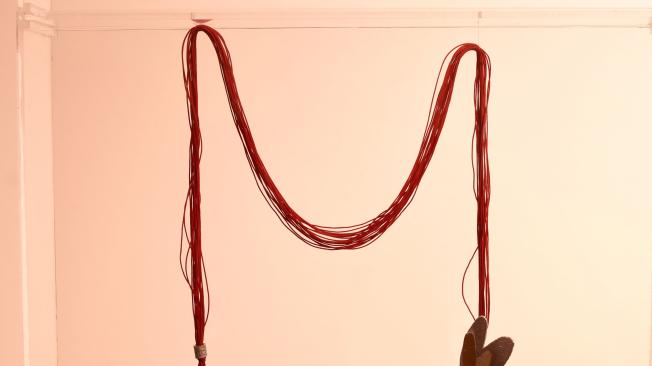 Collar con pin de plata de Johana de la Cruz. Cada cuerda representa una localidad de la ciudad.