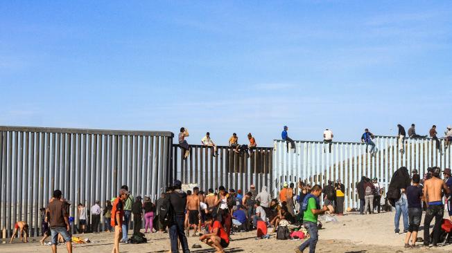 A pesar de la presencia de los agentes, una veintena de integrantes de la caravana migrante escaló los postes de metal que hacen la función de muro divisorio.