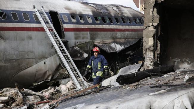 Un bombero camina entre los restos del fuselaje del avión.