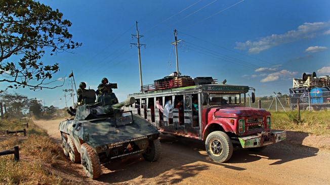 Zona Distención. San Vicente del Caguan (Caquetá – Colombia) enero 27 de 2012.  Un bus de trasporte público de pasajeros conocido como ‘chiva’ adelanta un tanque de combate del ejército Colombiano.