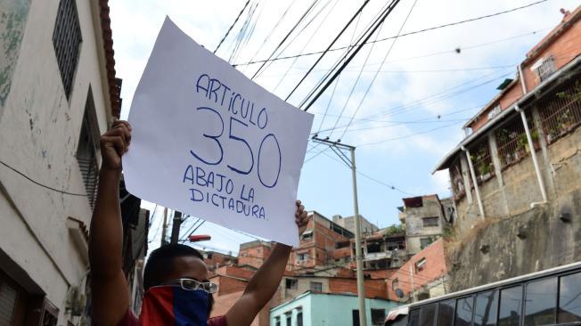 Un manifestante rechaza el gobierno del presidente Nicolás Maduro, señalándolo de "dictadura" en un cartel durante el cacerolazo en Caracas.