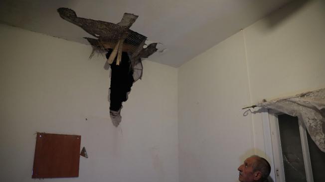Un hombre mira el daño al techo de la casa que fue golpeada por un cohete, cerca de la frontera de Gaza, en el sur de Israel.