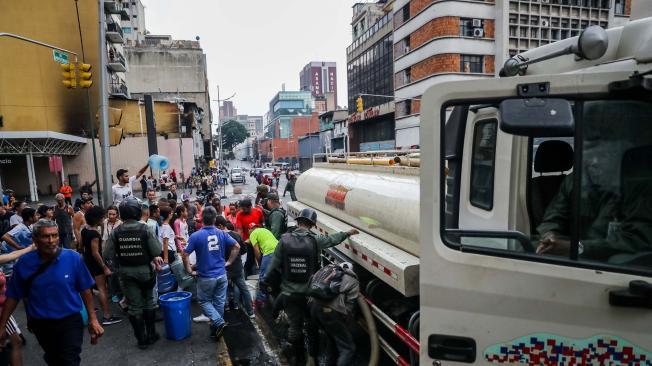 Un grupo de personas se aprovisiona de agua de un carrotanque, en el centro de Caracas.