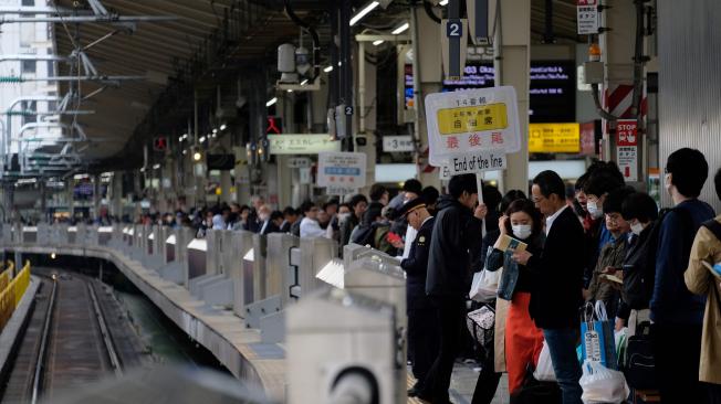 Cientos de pasajeros esperan en fila tomar el tren en la estación central de Tokio.