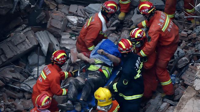 Los servicios de rescate trasladan a una víctima tras el derrumbe de un edificio este jueves en el centro de Shangái, China.