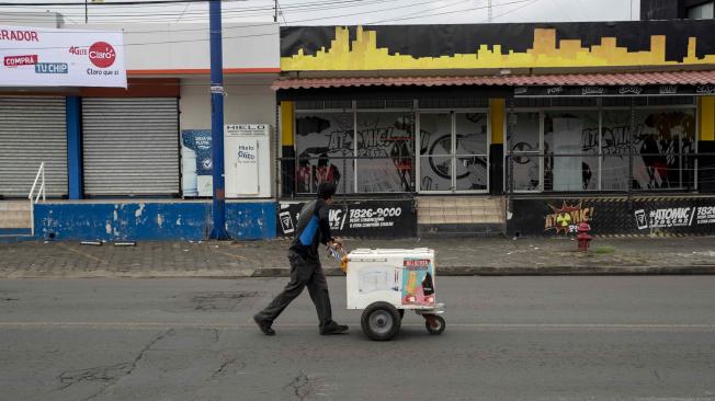 Un vendedor ambulante camina frente varios negocios cerrados durante el paro nacional en Nicaragua.