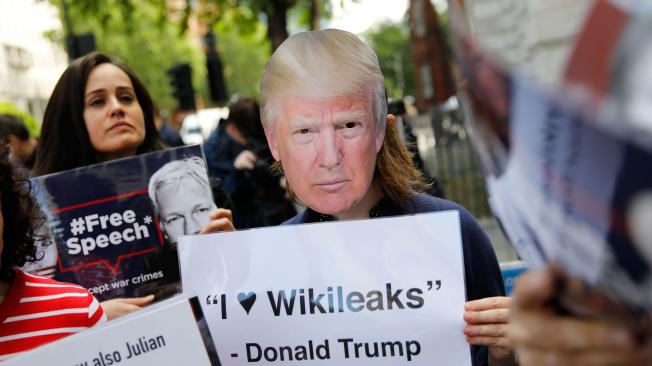 Seguidores de Julian Assange visten máscaras de Donald Trump y sostienen pancartas para demostrarle su apoyo durante su juicio en la Corte de Magistrados de Westminster.