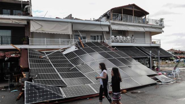Turistas pasan frente a un techo caído cubierto de paneles solares después de tormenta en Nea Plagia, en Chalkidiki, al norte de Grecia.