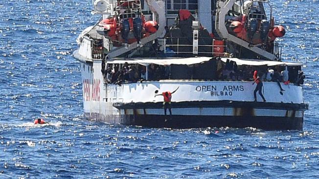 Los migrantes saltan del barco de rescate español Open Arms, cerca de la tienda italiana en Lampedusa,