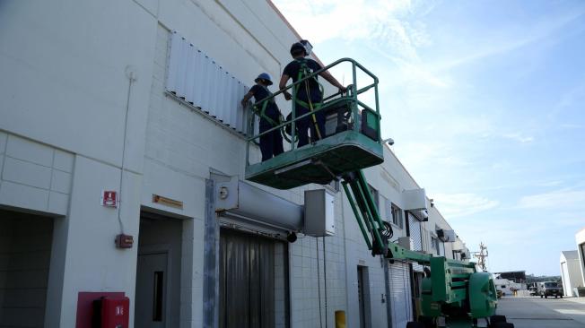 Profesionales de Ingeniería de Instalaciones cubren con metal las fachadas de algunos almacenes en Miami Beach, Florida ante la llegada del huracán Dorian.