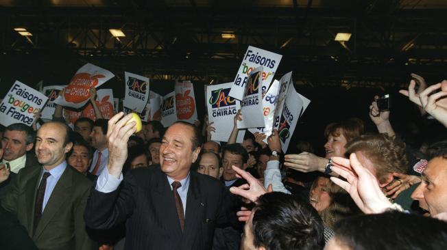 (ARCHIVOS) En esta foto de archivo tomada el 24 de marzo de 1995, el candidato presidencial francés Jacques Chirac sostiene una manzana en Burdeos durante una reunión de campaña electoral, mientras que Alain Juppe (2ndL), su director de campaña y su futuro primer ministro. El ex presidente francés Jacques Chirac murió a la edad de 86 años, se anunció el 26 de septiembre de 2019.