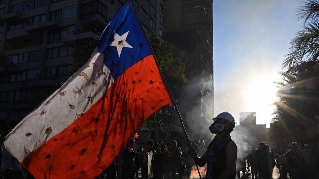 Un manifestante onde la bandera de Chile, donde las protestas comenzaron el 18 de octubre.