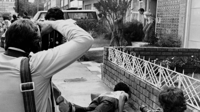 1 de marzo de 1980. La salida de residentes de una casa aledaña a la embajada causó confusión entre guerrilleros, rehenes, periodistas y agentes policiales fuera del edificio. En esta foto, un socorrista y un reportero gráfico aparecen tendidos mientras otros enfocan sus cámaras a la residencias.
