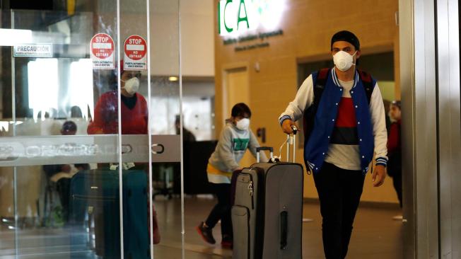 Viajeros nacionales e internacionales cubren sus rostros con tapabocas en el aeropuerto internacional El Dorado por la pandemia del coronavirus.