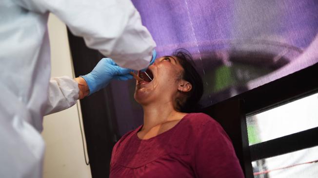 Un trabajador de la salud usa un hisopo para recolectar una muestra para la prueba de coronavirus en el mercado Central de Abastos en la Ciudad de México.
