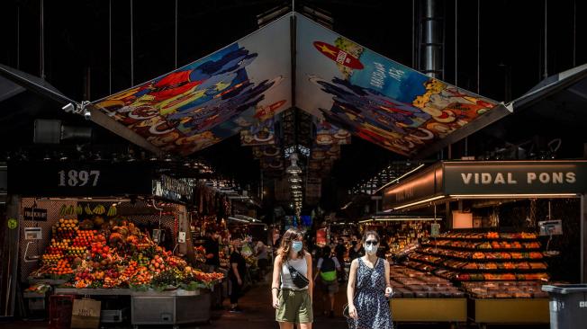 Dos turistas salen del tradicional mercado de la Boquería, en Barcelona, ciudad muy golpeada por el virus.