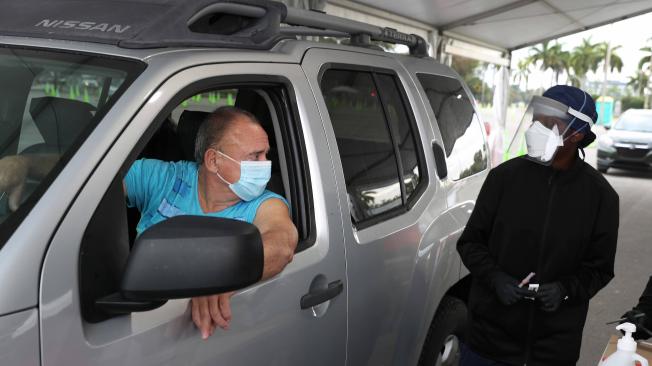 Un habitante de Florida se prepara para recibir una vacuna COVID-19 de un trabajador de la salud en un sitio de drive-thru en Tropical Park el 13 de enero de 2021 en Miami.