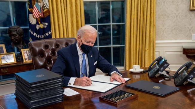 Joe Biden, presidente de Estados Unidos, firma órdenes ejecutivas desde la Oficina Oval.