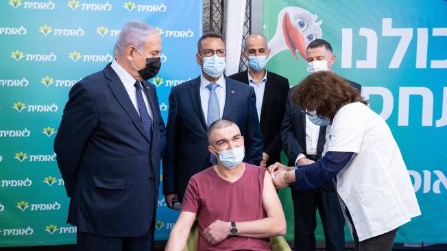 El primer ministro israelí, Benjamin Netanyahu (izq.), aparece junto a quien, según el gobierno, es la persona número cuatro millones en recibir una vacuna contra el coronavirus, durante su visita a las instalaciones del Leumit Health Care Services en Jerusalén.