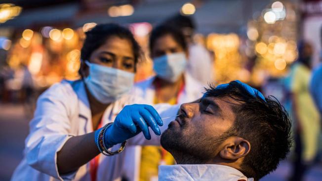 Un trabajador de la salud recolecta una muestra de hisopado nasal de un devoto hindú para realizar la prueba del coronavirus Covid-19 durante el festival religioso Kumbh Mela en curso, en Haridwar.