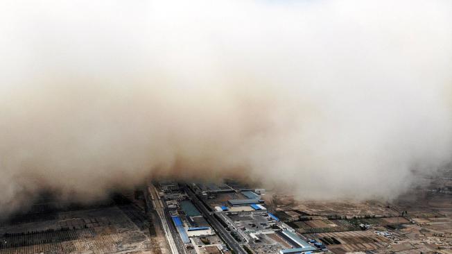 Esta foto aérea tomada el 25 de abril de 2021 muestra una tormenta de arena envolviendo una aldea en el condado de Linze, en la ciudad de Zhangye en la provincia de Gansu, noroeste de China.