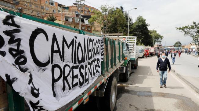 Decenas de personas tratan de llegar a sus destinos caminando por el bloqueo de vías realizado por conductores de camiones que participan de una nueva jornada de protesta. EFE/ Carlos Ortega