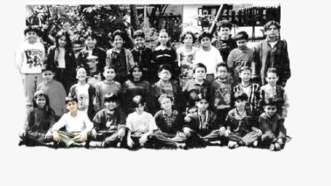 Lucas está sentado en la primera fila. Es el segundo de izquierda a derecha con camisa blanca, La foto es de su curso en 1995 en el Instituto Merani.