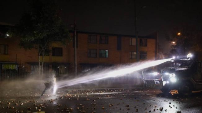 En el Portal de las Américas, un manifestante se resguarda del chorro de agua usado por el Esmad para controlar las protestas.