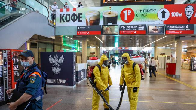 Trabajadores del ministerio de situaciones de emergencia de Rusia rocían una solución desinfectante en la explanada durante una operación de limpieza profunda en la estación de tren de Leningradsky en Moscú.