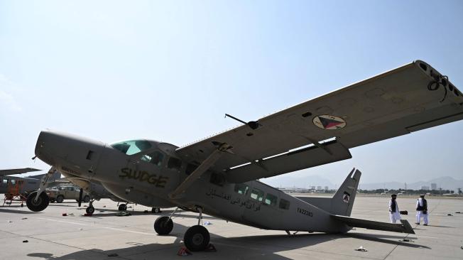Miembros del Talibán pasan junto a un avión dañado en el aeropuerto de Kabul el 31 de agosto de 2021.