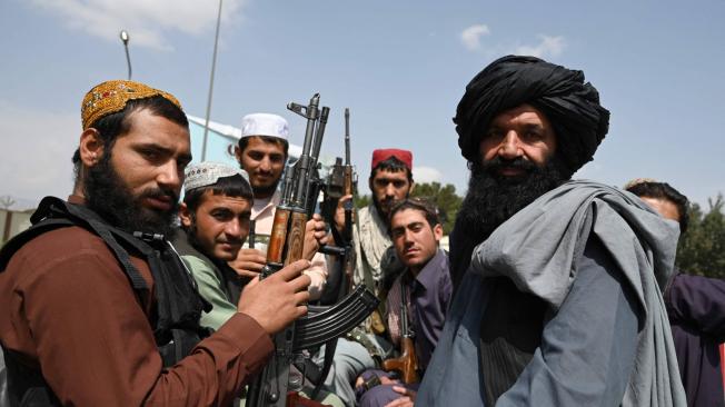 Talibanes lucen sus armas mientras están montados en una camioneta.