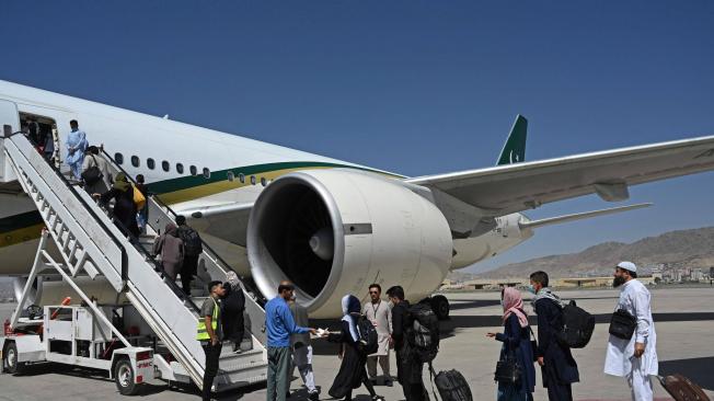 Pasajeros abordan un vuelo de Pakistán International Airlines (PIA), el primer vuelo internacional comercial desde que los talibanes recuperaron el poder, en el aeropuerto de Kabul el 13 de septiembre de 2021