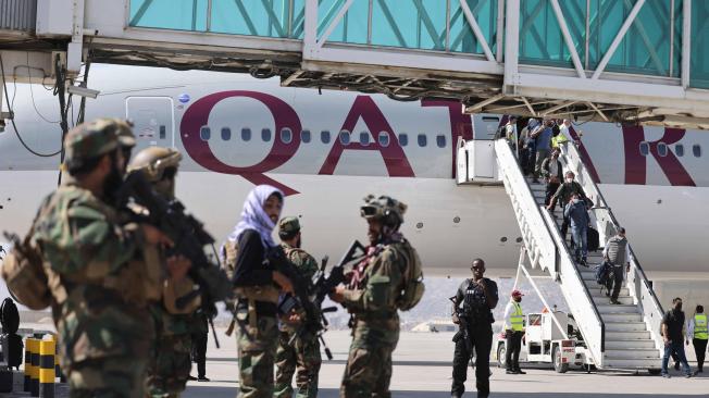 Combatientes talibán Badri 313 en guardia mientras los pasajeros desembarcan un avión de Catar, en Kabul el 14 de septiembre de 2021