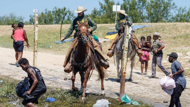 Agentes montados de EE. UU. evitan que inmigrantes haitianos ingresen a un campamento a orillas de Río Grande.