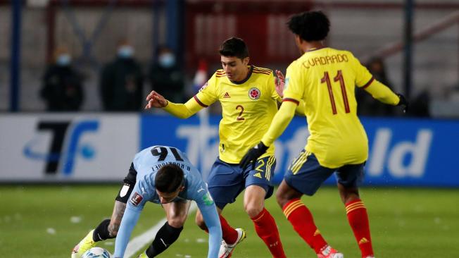 Brian Rodríguez (i) de Uruguay disputa un balón con John Medina (c) y Juan Cuadrado de Colombia en partido de eliminatorias para Catar 2022.