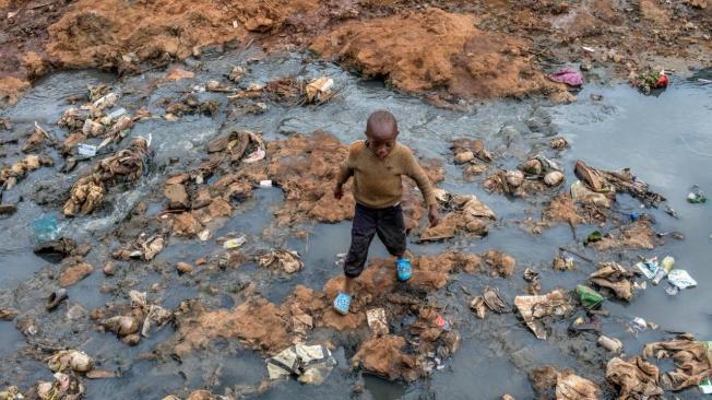 Un niño atraviesa un drenaje contaminado en Kenia. Los efectos climáticos amenazan el agua y la seguridad alimentaria mundial.