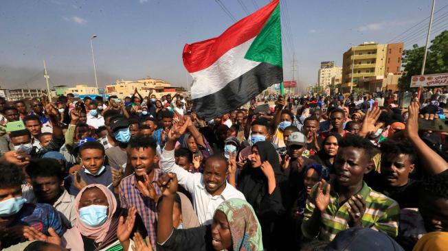 Manifestantes sudaneses levantan banderas nacionales mientras se manifiestan en Jartum para denunciar las detenciones nocturnas por parte del ejército de miembros del gobierno, el 25 de octubre de 2021.