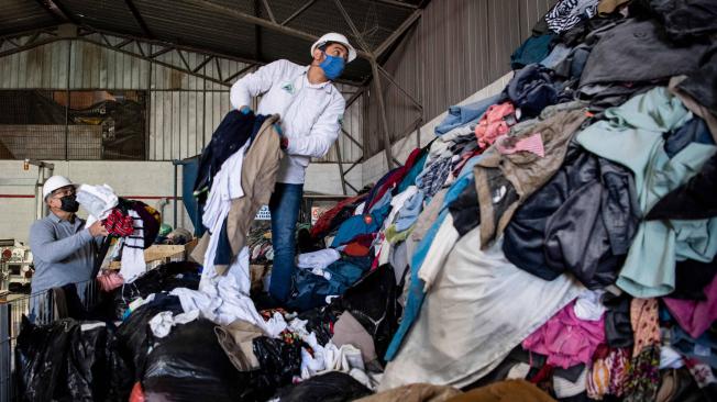 Hombres trabajan en una fábrica que recicla ropa usada desechada en el desierto de Atacama para paneles de aislamiento de madera para los muros de viviendas sociales, en Alto Hospicio, Iquique, Chile, el 27 de septiembre de 2021.