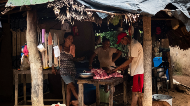Luis Alberto Ramos Arciniegas, a la derecha, trabaja en un cultivo de palma haciendo oficios variados. En sus ratos libres, le vende cerdo a la comunidad. Dice que hoy respiran con mayor tranquilidad.