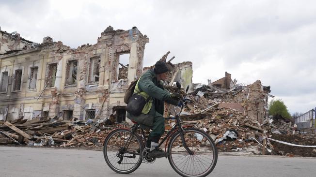Un hombre ucraniano  monta en bicicleta frente a un edificio de bombardeo destruido en Kharkiv, Ucrania, el 24 de abril de 2022, en medio de la invasión rusa.