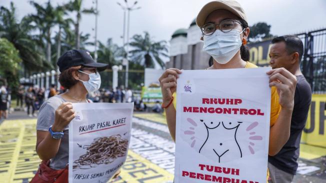 Manifestante sostiene un cartel que dice 'La ley penal controla el cuerpo de la mujer' durante protestas a las reformas en Indonesia.