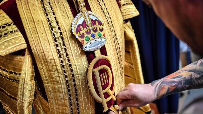 Un trabajador inspecciona la capa de Estado del Tambor Mayor adornada con el nuevo escudo de CR III y que se lucirá durante la Coronación del Rey Carlos III.