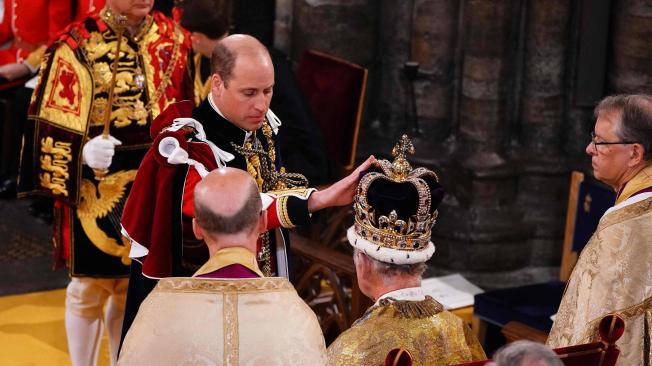 El Príncipe Guillermo de Gran Bretaña, príncipe de Gales, toca la corona de San Eduardo en la cabeza de su padre.