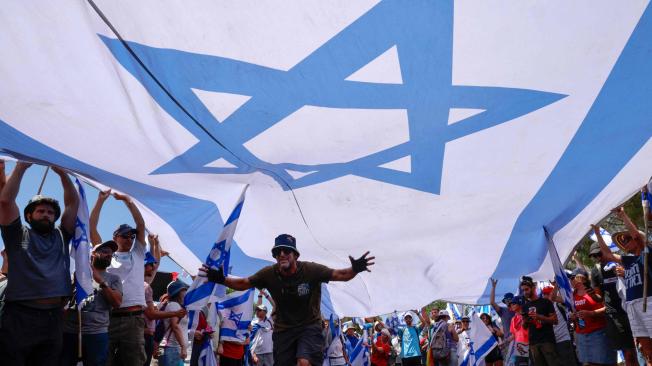 Manifestantes izan una gran bandera nacional durante una manifestación cerca de la Knesset, el Parlamento israelí.