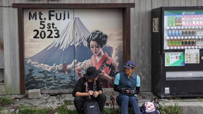 Esta foto tomada el 31 de agosto de 2023 muestra a dos visitantes descansando en la quinta etapa en las laderas del Monte Fuji, el pico más alto de Japón con 3.776 metros (12.388 pies).