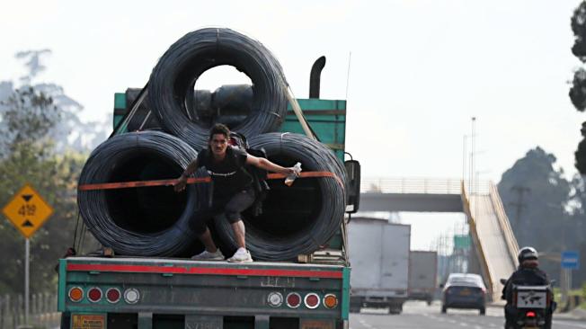 Hombre en aparente estado de alcoholismo va colgado de una tractomula.