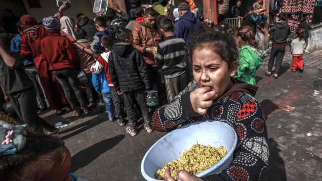 Niños palestinos desplazados se reúnen para recibir alimentos en una escuela pública de Rafah.
