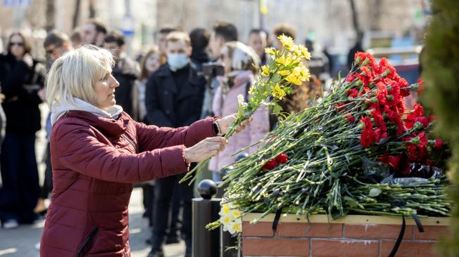 Una mujer deposita flores frente a la embajada rusa en señal de condolencias tras el atentado terrorista en la sala de conciertos Crocus City Hall de Krasnogorsk.